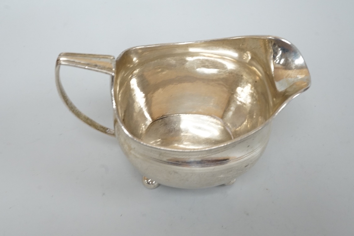 A George III silver cream jug, on four ball feet, London, 1812, 95mm, with engraved foliate band, maker's mark rubbed.